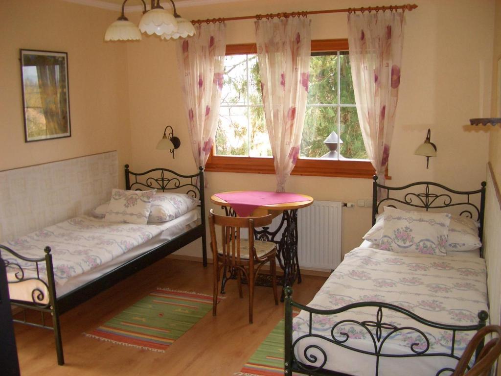凯希道库什塔尼Bundi Vendégház的一间卧室设有两张床、一张桌子和一个窗口