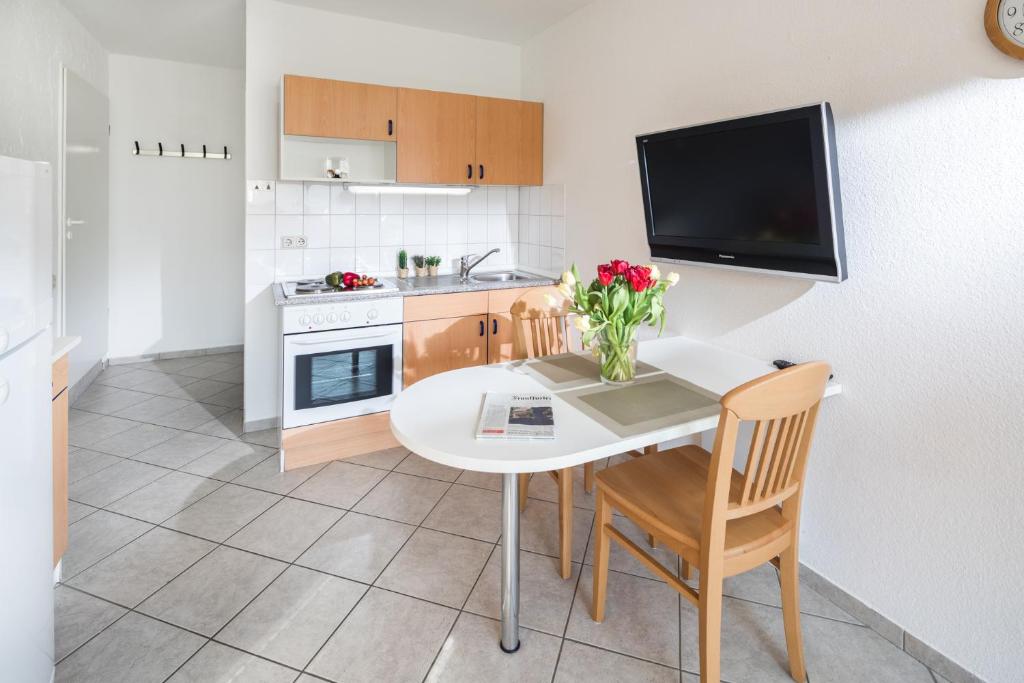 诺德奈Birkenhof的厨房配有白色的桌椅和电视。