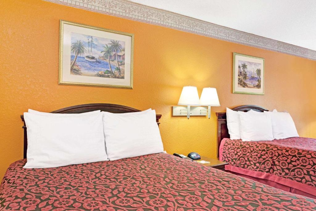 代托纳海滩Sunset Inn Daytona Beach的酒店客房带两张床和橙色墙壁