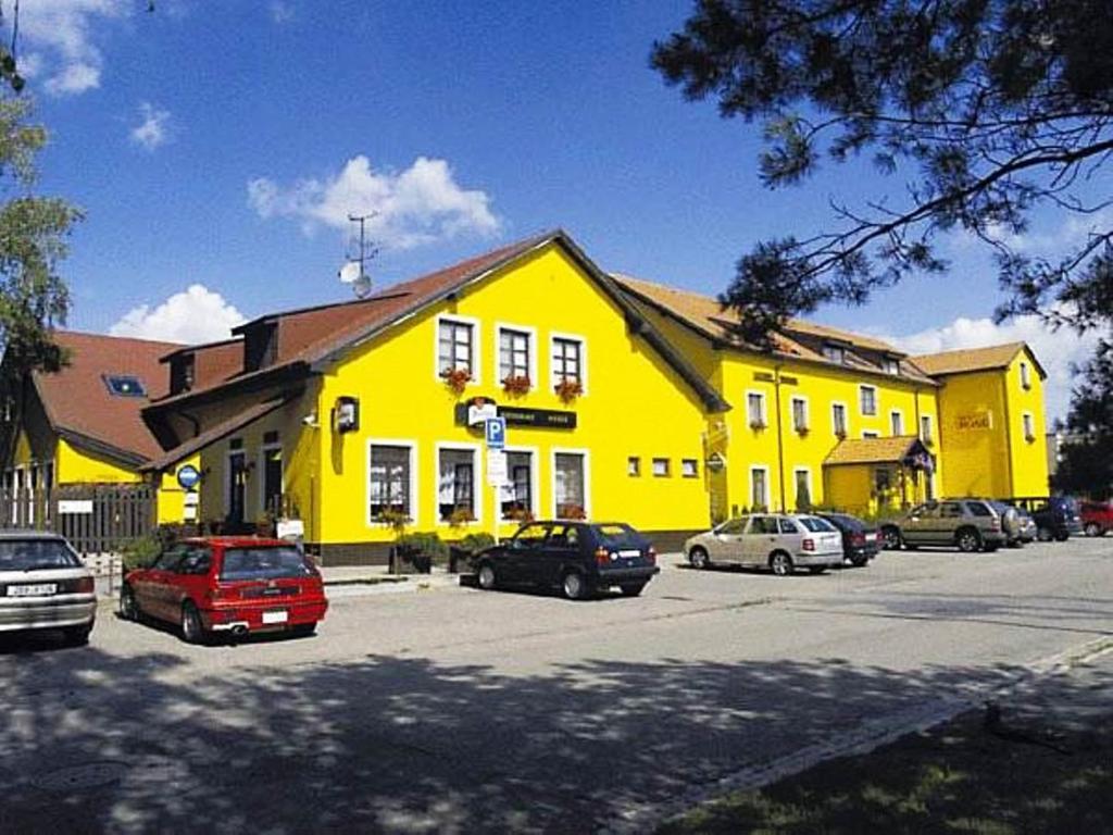 布热茨拉夫Hotel ROSE Břeclav的一座黄色的建筑,汽车停在停车场