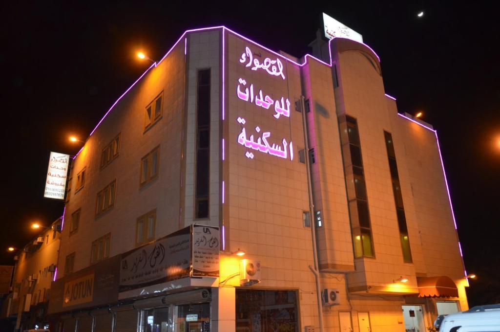 布赖代Al Qaswaa Furnished Apartements的建筑的侧面有 ⁇ 虹灯标志