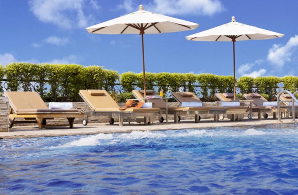 芭堤雅市中心Intimate Hotel Pattaya - SHA Extra Plus的一组椅子和遮阳伞,位于游泳池旁