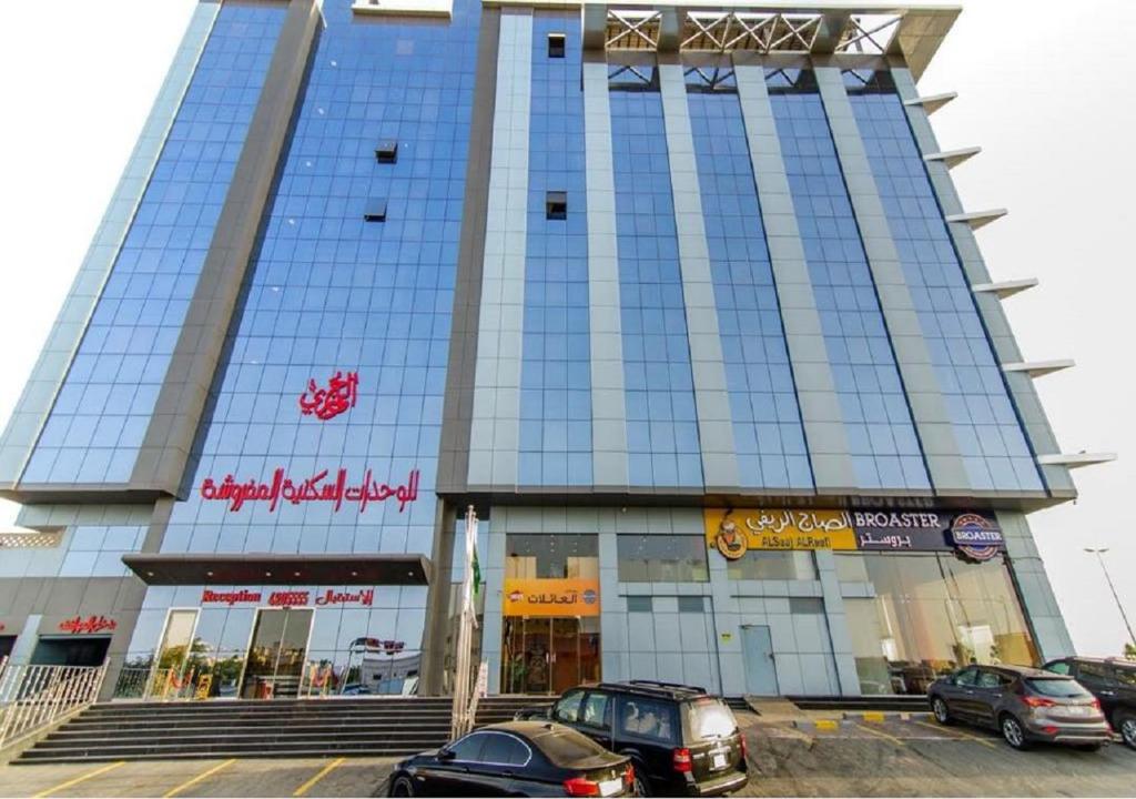 吉达Al Joury Aparthotel的一座大型建筑,前面有汽车停放