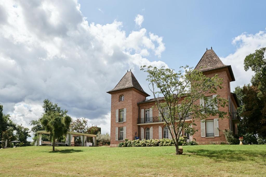 蒙托邦Castel Bois Marie, Maison d'hôtes的前面有一棵树的大型砖砌建筑