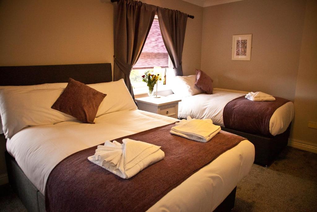 切斯特Rowton Poplars Hotel的酒店客房设有两张床和窗户。