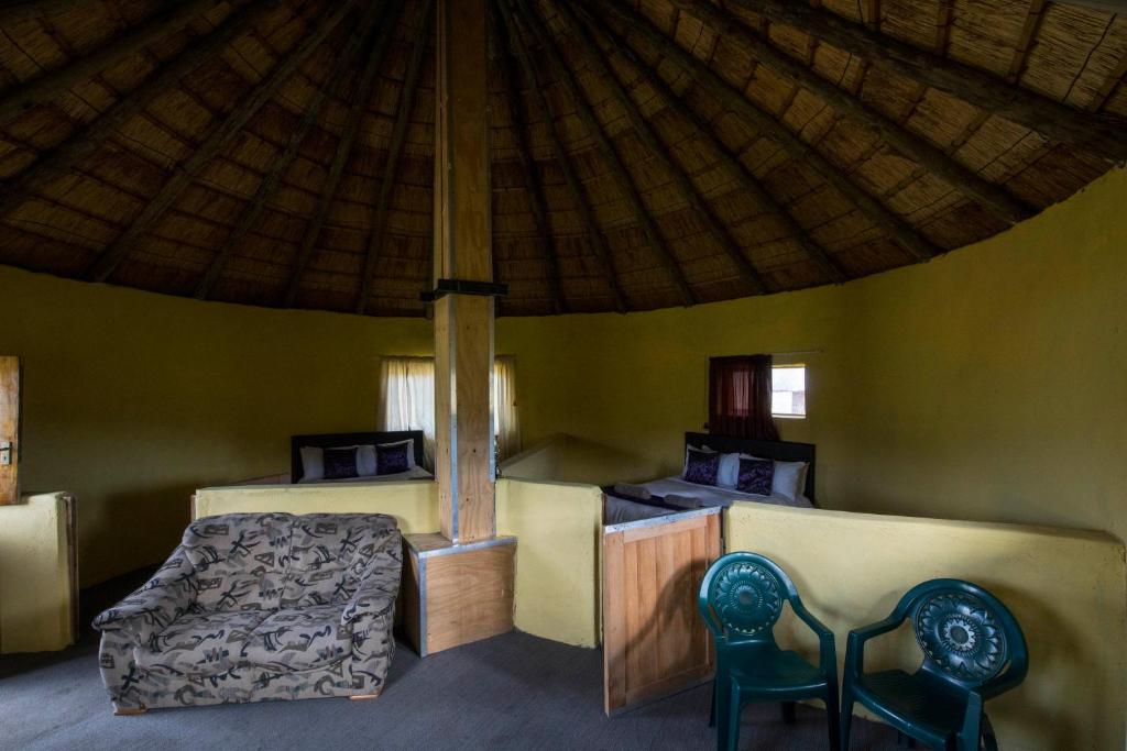 MokhotlongSani Stone Lodge的一间卧室配有一张床,帐篷内配有两把椅子