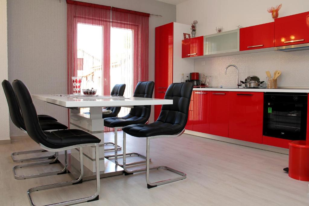 比利切Apartmani Corleone的厨房配有红色橱柜和一张带黑色椅子的白色桌子
