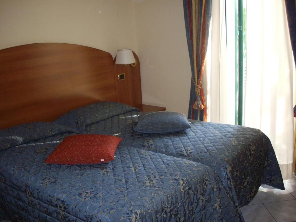 阿尔玛·迪·塔吉亚Ristorante Albergo Roma的一间卧室配有一张蓝色的床和红色枕头
