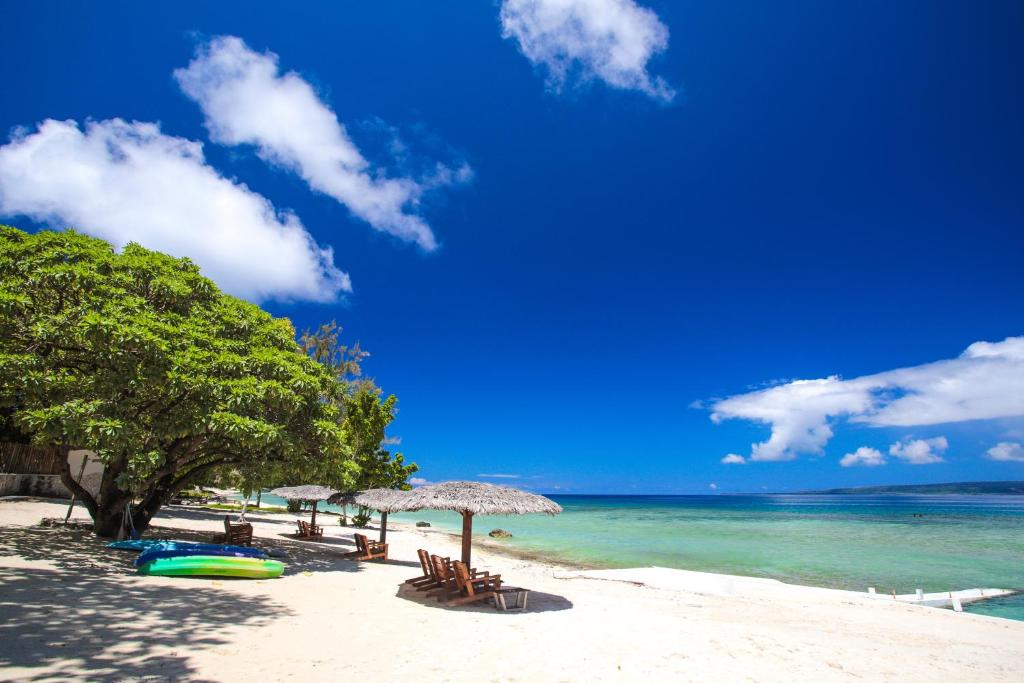 维拉港Coco Beach Resort的海滩上设有椅子和遮阳伞,还有大海