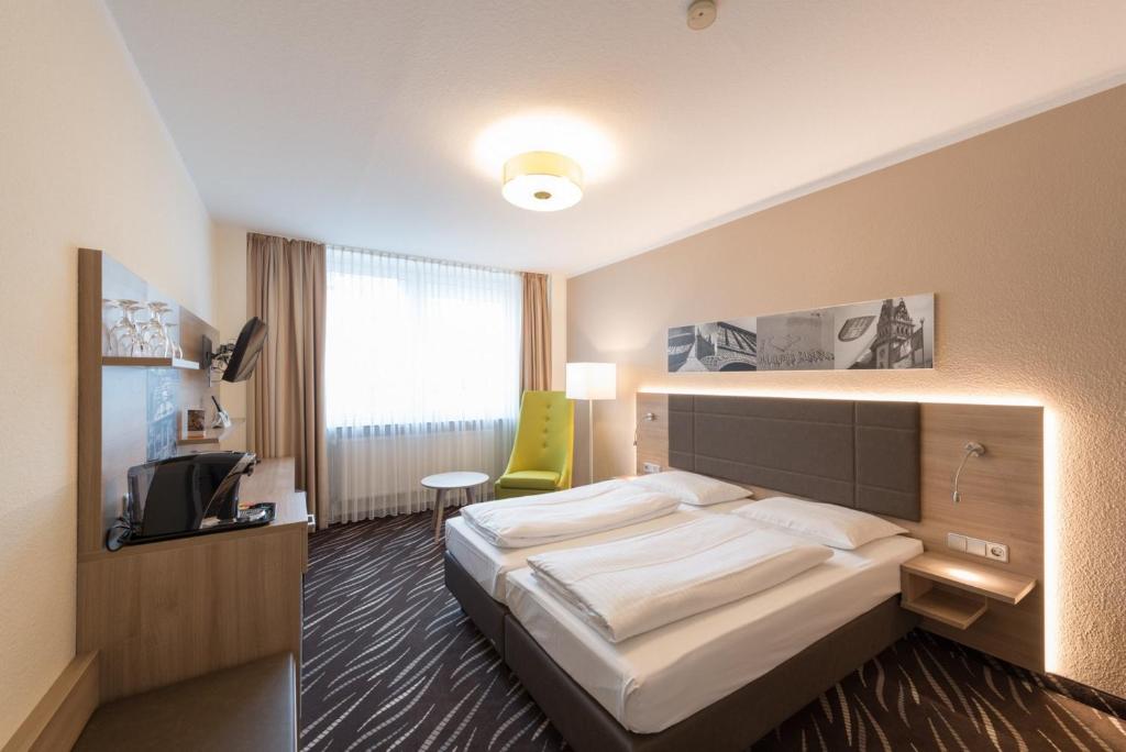 汉堡黑科托城市公园住宿酒店的酒店客房,配有床和黄色椅子