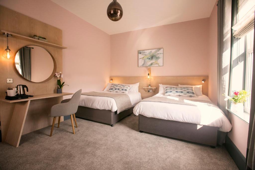 巴林托伊富勒顿纹章酒店的一间卧室配有两张床、一张桌子和一面镜子