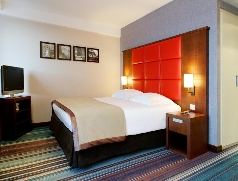 布鲁塞尔New Hotel Charlemagne的配有一张床和一台平面电视的酒店客房