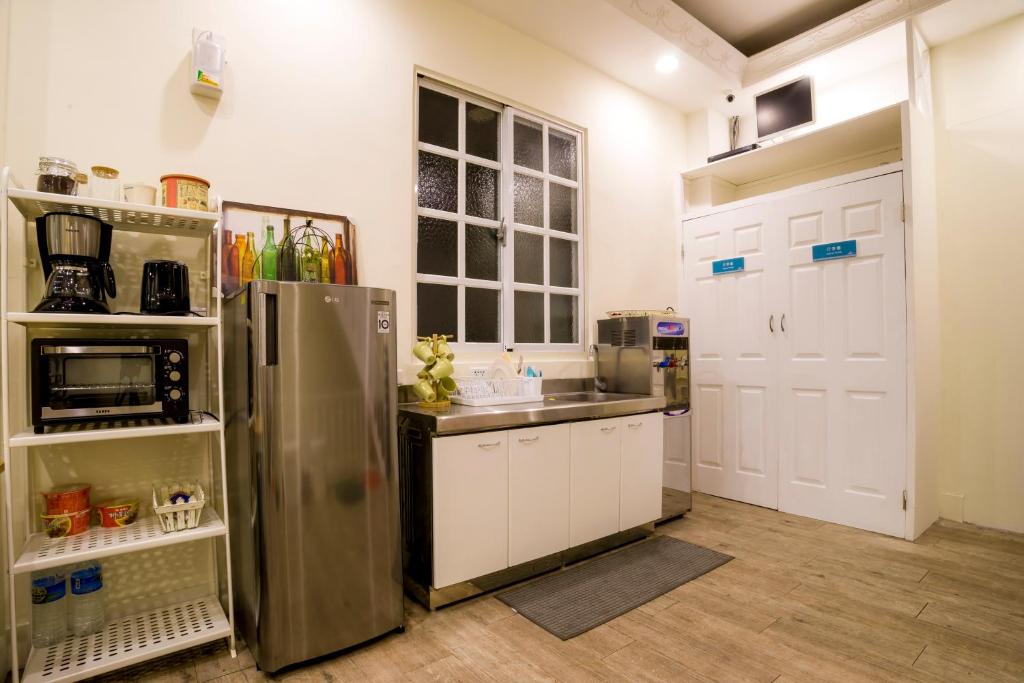 花莲市花莲鸟窝青年旅舍的厨房配有不锈钢冰箱和白色橱柜