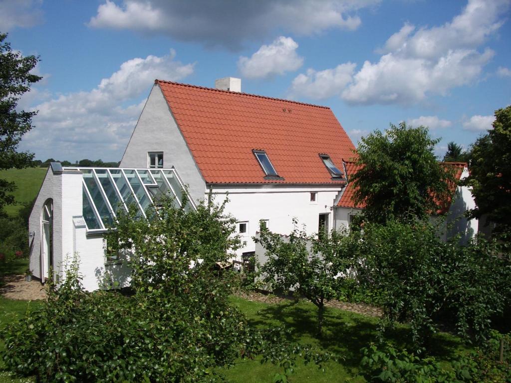 ThemNatursti Silkeborg Bed & Breakfast的白色的房子,有红色的屋顶,有温室