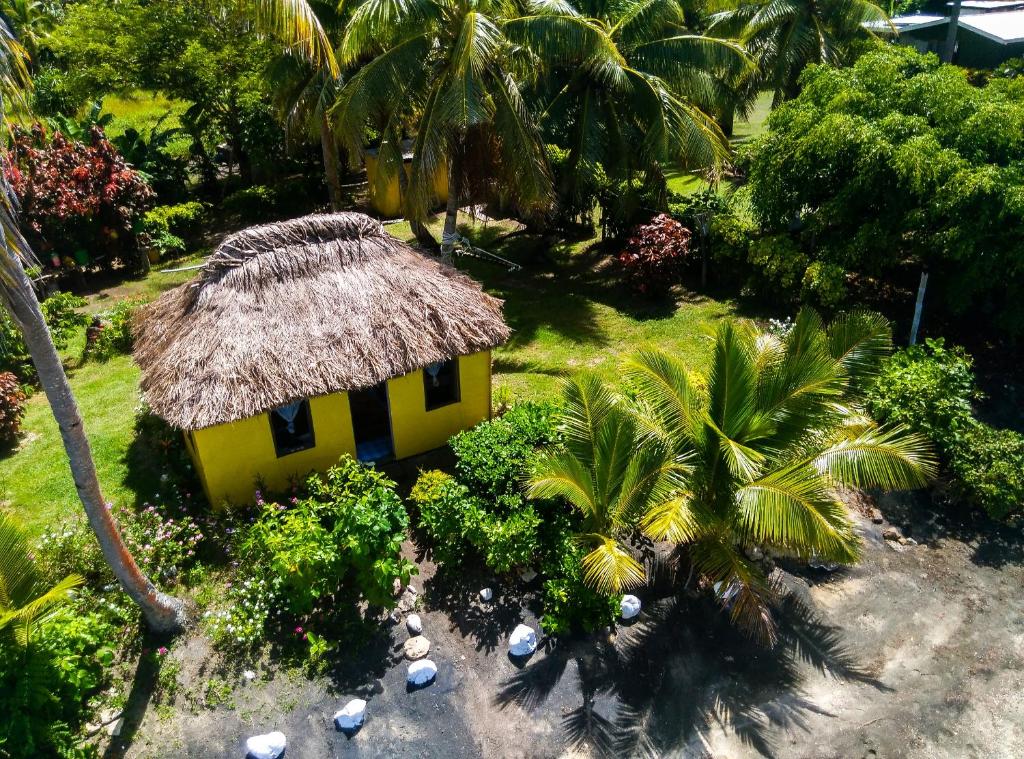 纳库拉岛亚撒瓦民宿的一座黄色的小房子,屋顶稻草,棕榈树