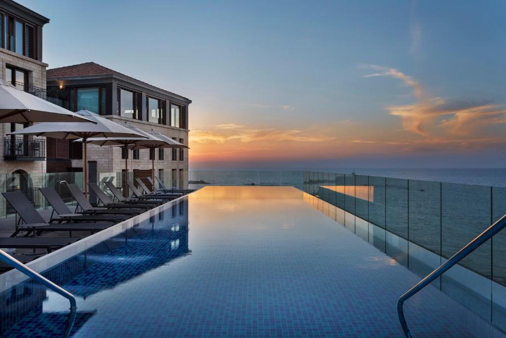 特拉维夫The Setai Tel Aviv, a Member of the leading hotels of the world的一个带椅子的游泳池,日落时分享有海景