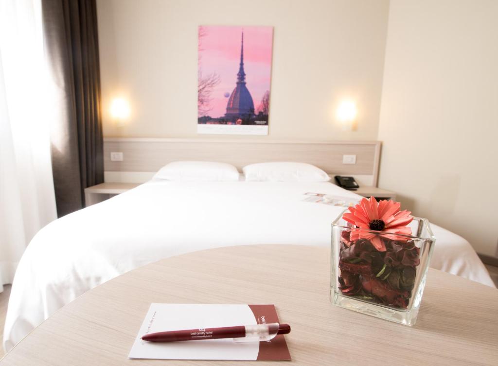 都灵都灵理工大学最佳品质酒店的一间卧室配有一张床和一张桌子及一支笔