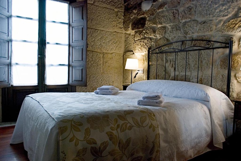 阿拉力兹A Lareira De Allariz的卧室配有一张石墙内的大床