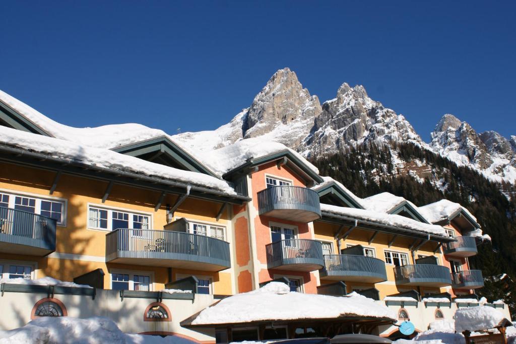圣马蒂诺-迪卡斯特罗扎史波堤俱乐部公寓酒店的一座被雪覆盖的建筑,背景是群山