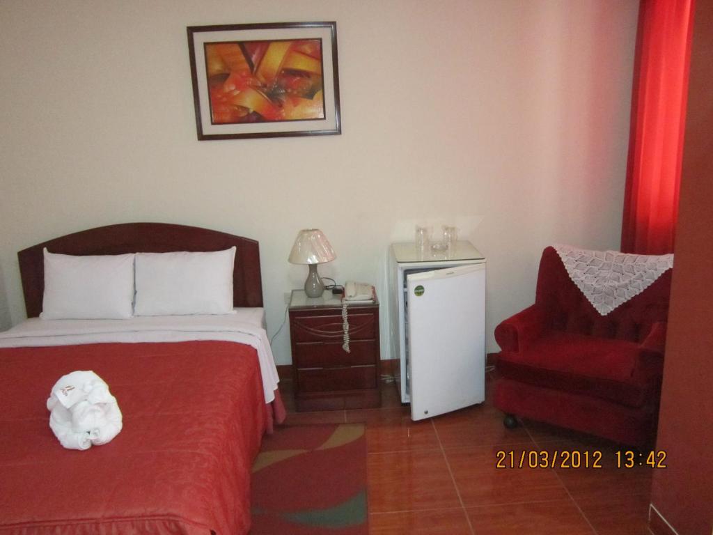 特鲁希略Hotel Plaza Trujillo的一间卧室配有一张床和一张红色椅子