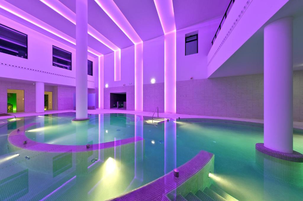 奥维罗巴拉加里斯URH温泉禅酒店的一座紫色照明的建筑中的室内游泳池