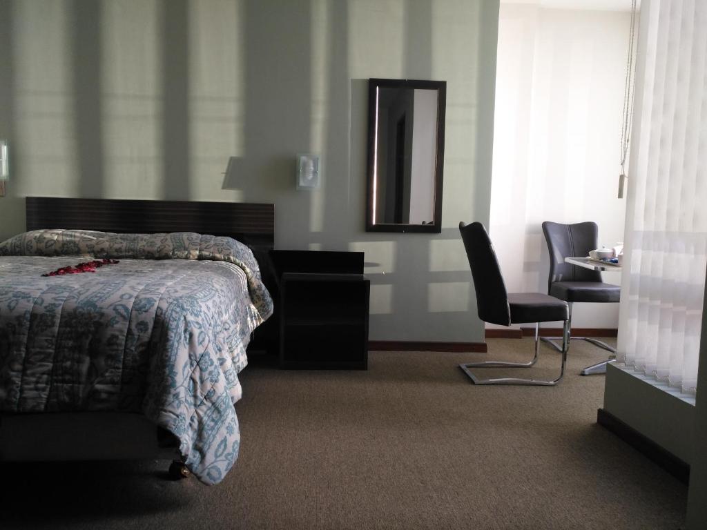 科恰班巴Hostal Costa De Marfil Suites & Apartamentos的一间卧室配有一张床、镜子和椅子