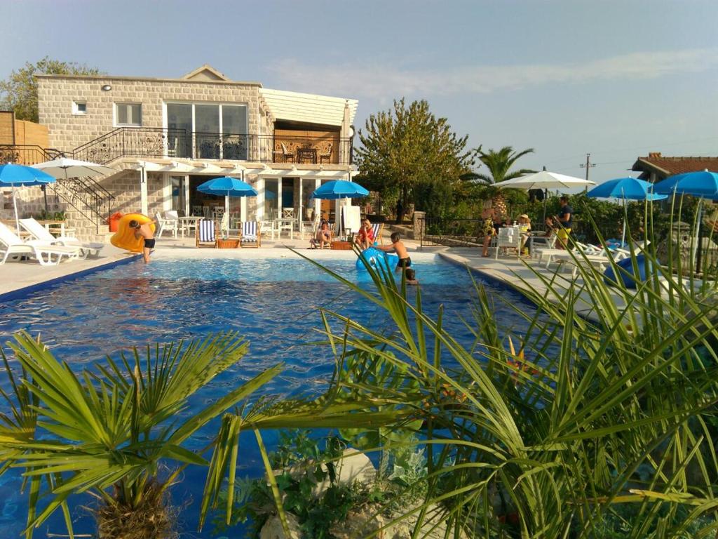 卢什蒂卡Luštica Apartments的一个带蓝伞的游泳池和一个房子