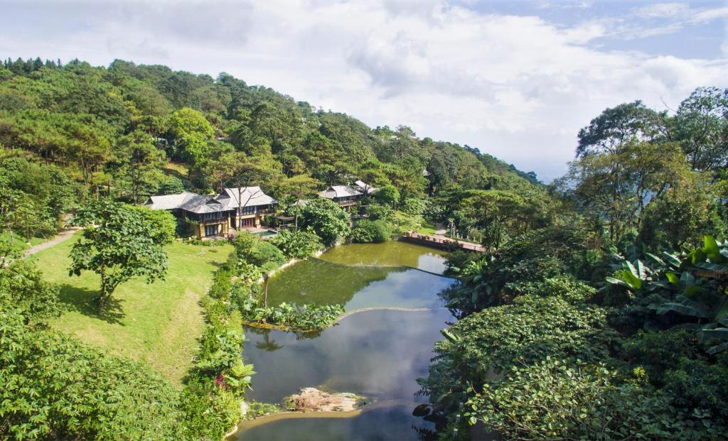 河内Melia Ba Vi Mountain Retreat的享有河边山丘上房屋的空中景致