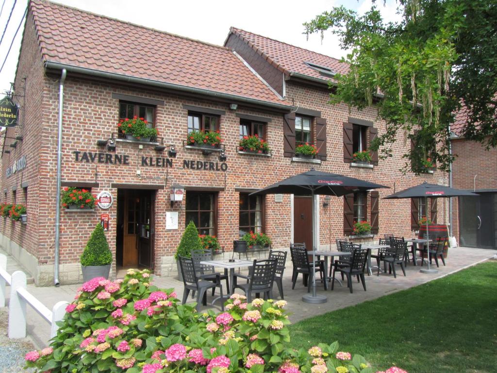 Vlezenbeek克莱恩尼德罗酒店的大楼前设有桌椅的餐厅