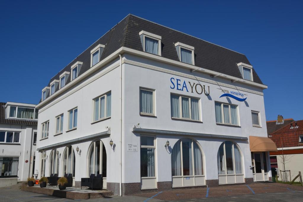 海滨诺德韦克SEA YOU Hotel Noordwijk的白色的建筑,旁边标有标志