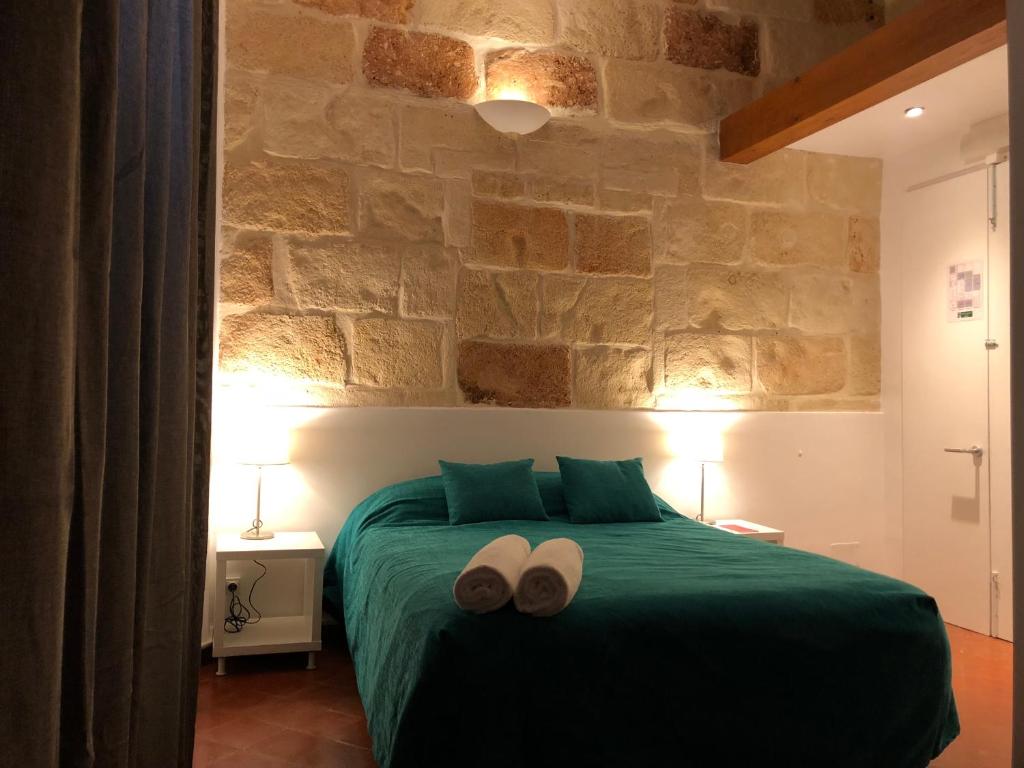 休达德亚Hostel Menorca的一间卧室配有绿床和2条毛巾