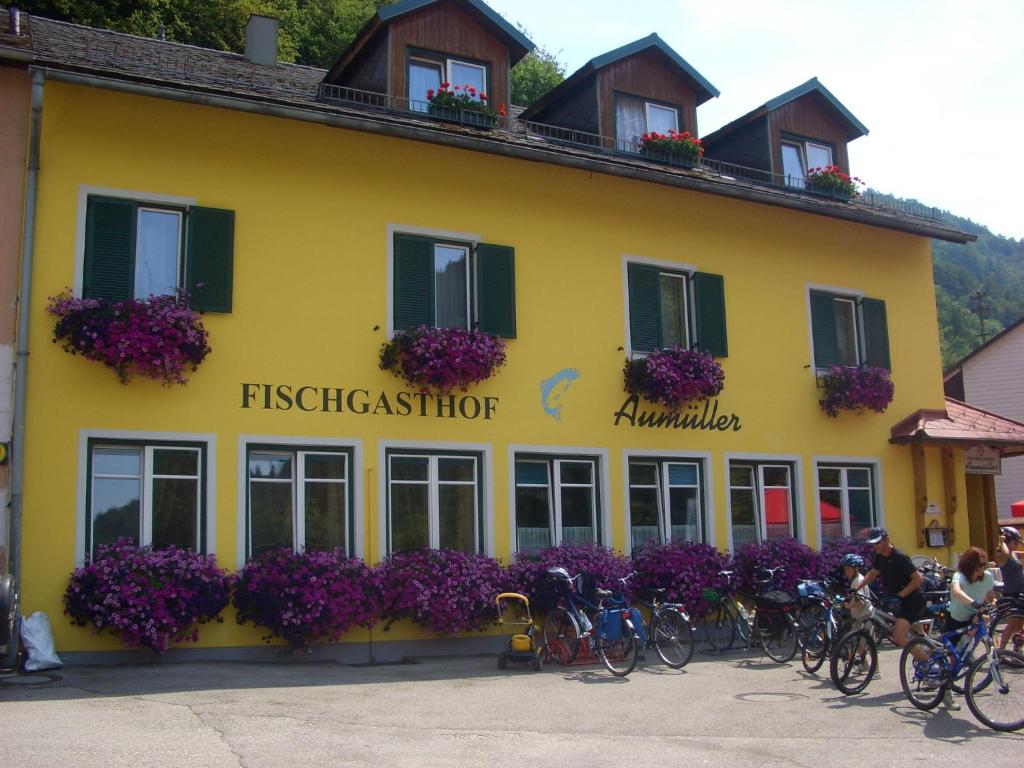 ObermühlFischgasthof Aumüller的一座黄色的建筑,前面有自行车停放