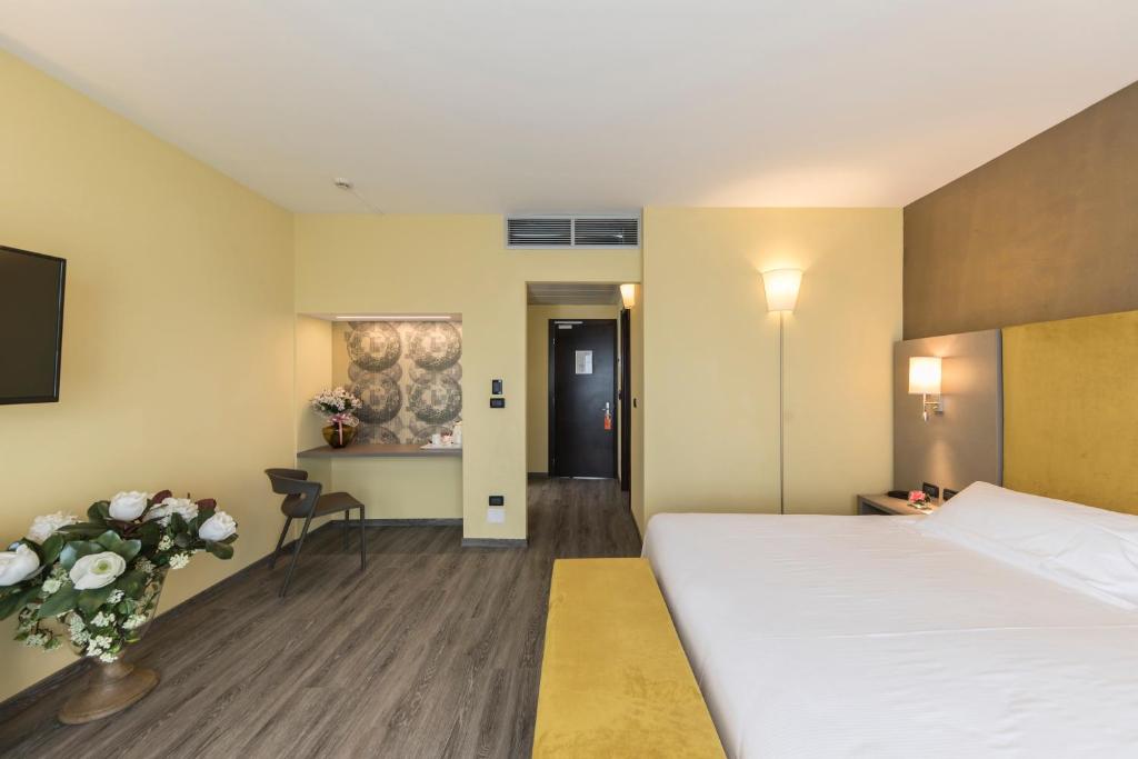 伊莫拉唐纳特洛伊莫纳酒店的酒店客房设有一张大床和一张桌子。