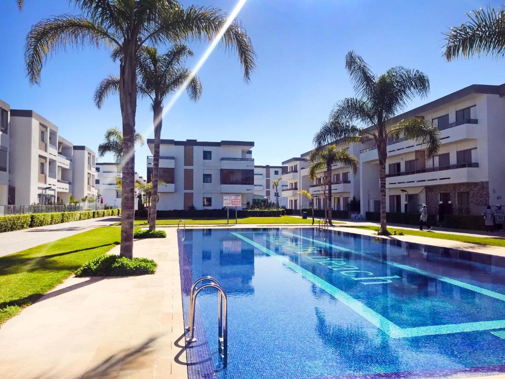 曼苏里亚Marbella Beach location pour famille 2 chambres的一座棕榈树和建筑游泳池