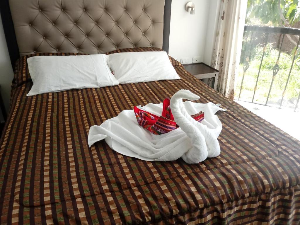 乌鲁班巴Hotel Quilla House 2的床上有毛巾和天鹅