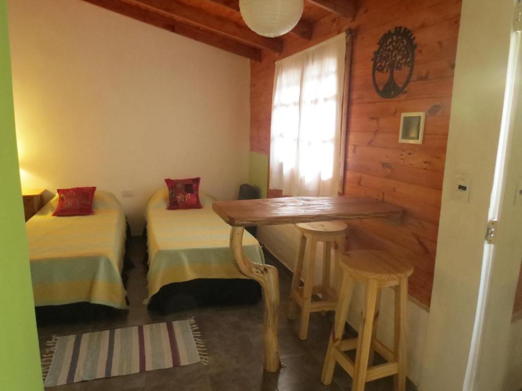 埃博森La Casa De La Abuela Departamentos的一间设有两张床、一张桌子和凳子的房间