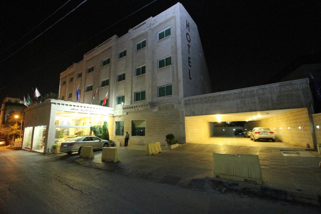 安曼阿尔萨拉亚酒店的一座有汽车在晚上停在停车场的建筑