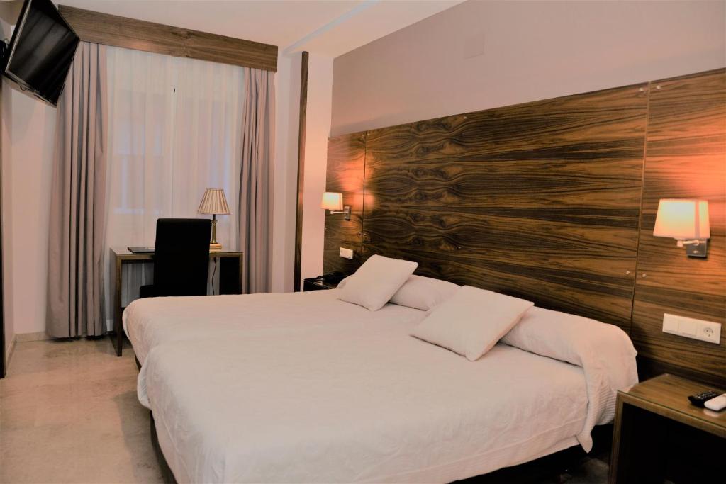 雷阿尔城埃斯库德罗酒店的酒店客房设有一张大床和木墙