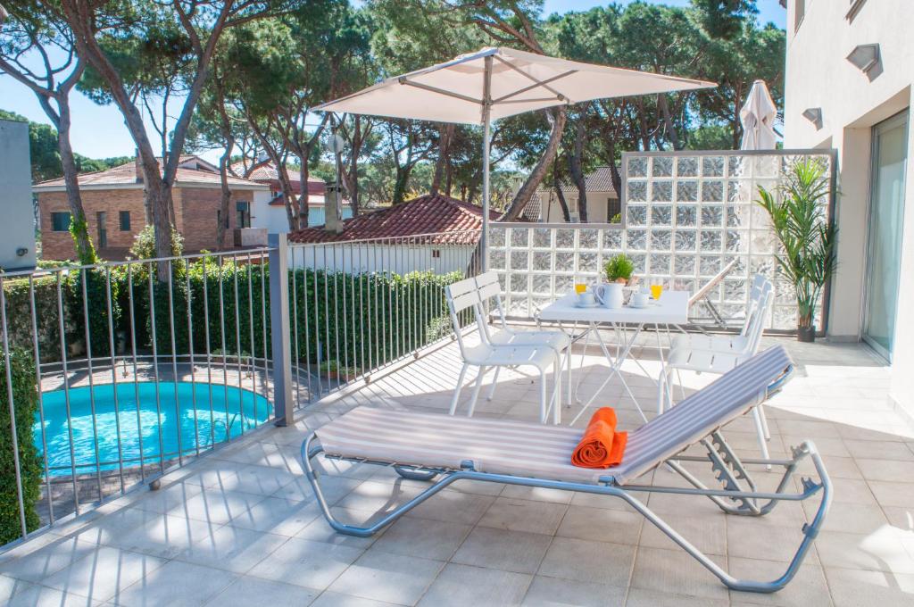 卡斯特尔德费尔斯波塔科伊利公寓的一个带桌子和遮阳伞的庭院,毗邻一个游泳池