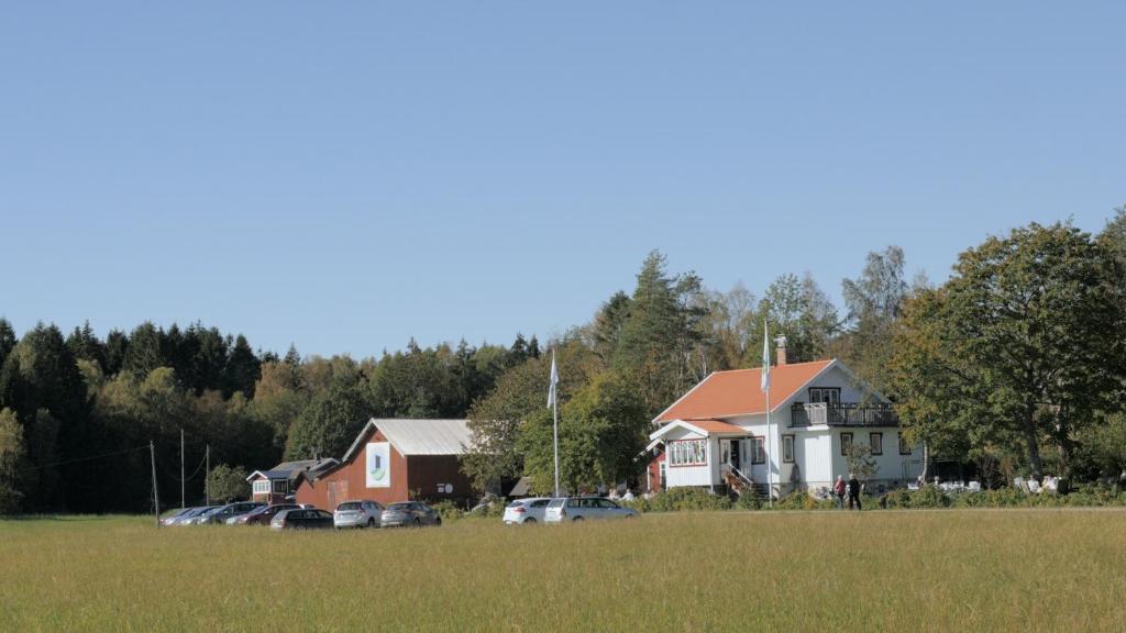 TegnebyTavlebords Honungsgård的田野里的房子,汽车停在田野里