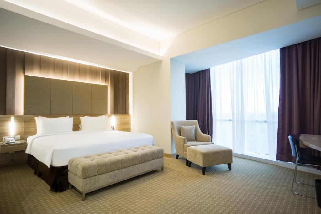 雅加达Grand G7 Hotel Kemayoran的配有一张床和一把椅子的酒店客房