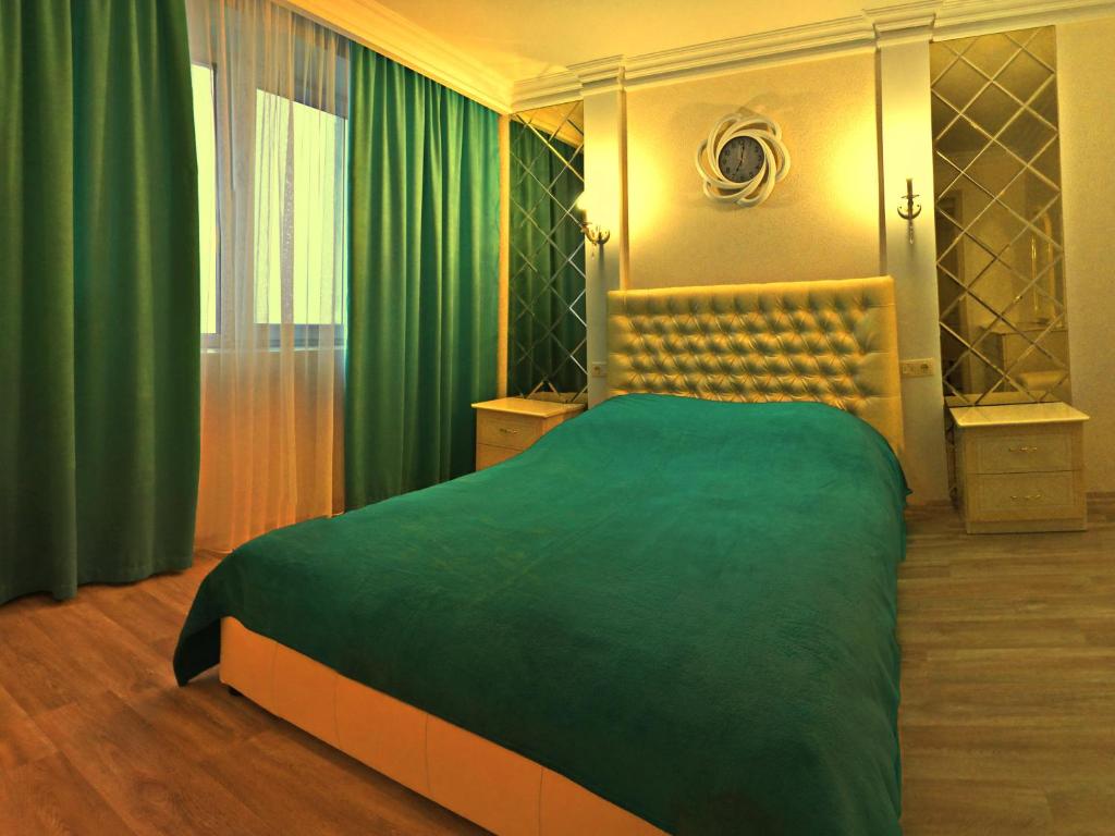 切尔尼戈夫ApartLux 2的一间卧室配有一张带绿毯的大床