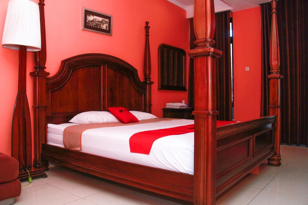 万隆赛尔森巴胡里红门旅馆的一间卧室设有一张带红色墙壁的大床