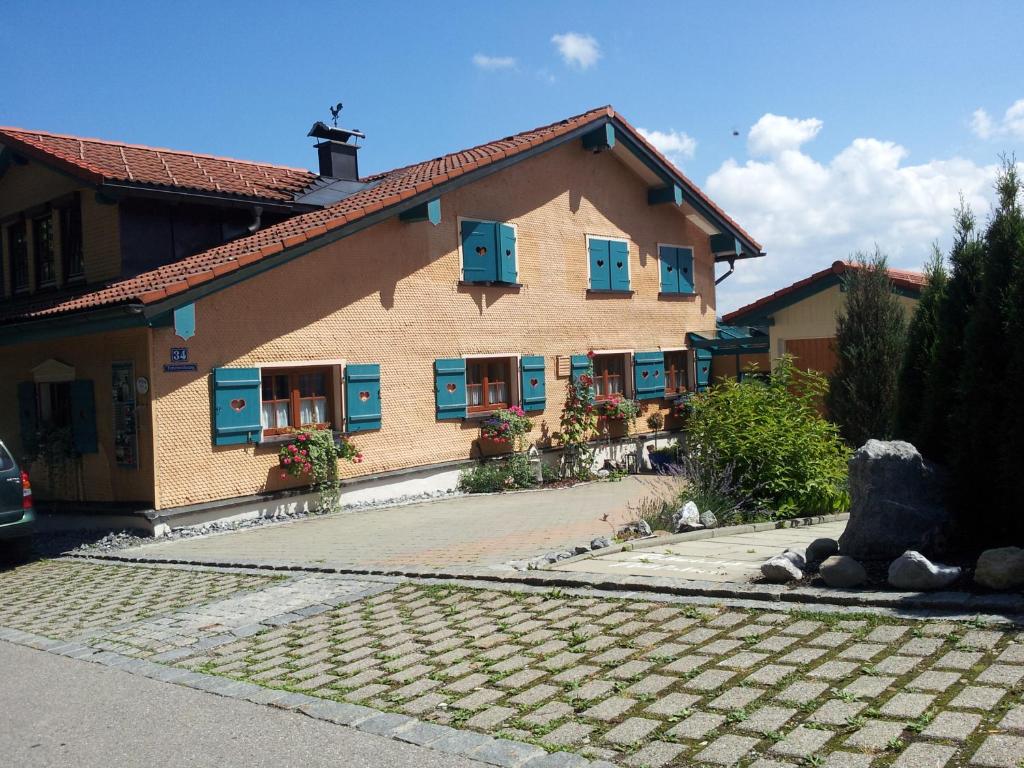 上罗伊特Gästehaus-Einkehr的一座大型建筑,设有蓝色窗户和鹅卵石车道