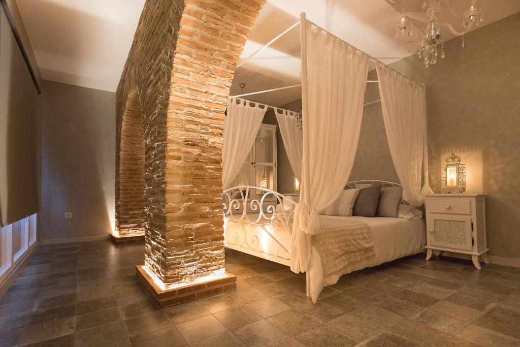 阿尔科斯-德拉弗龙特拉Hotel Posada de las Cuevas的一间卧室设有天蓬床和砖墙