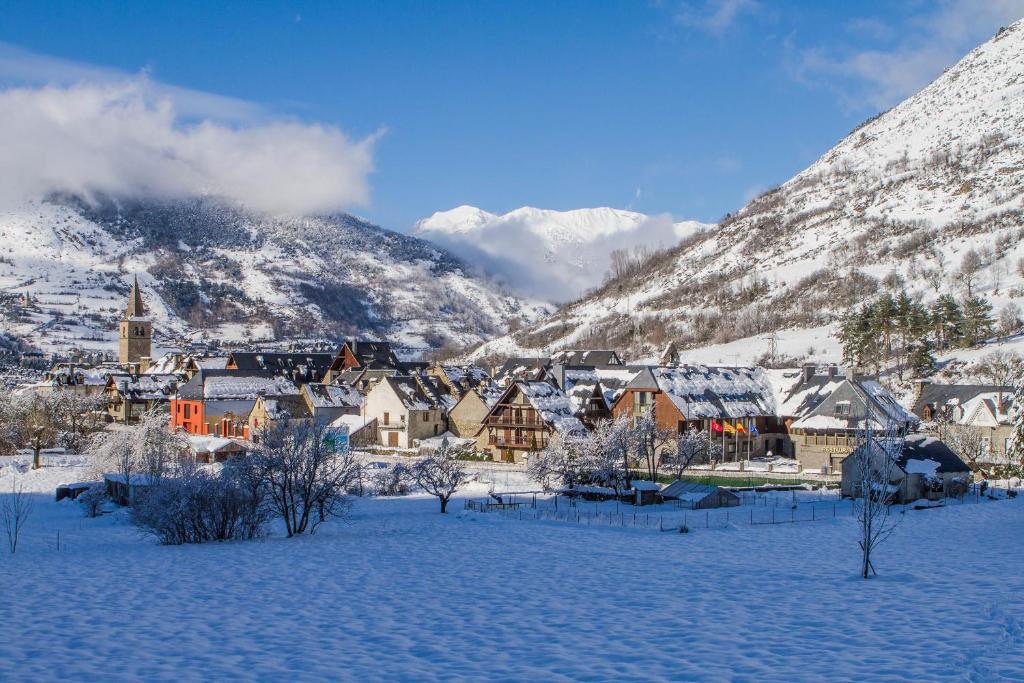 维耶拉Gran Chalet Hotel & Petit Spa的一座被雪覆盖的小镇,以群山为背景