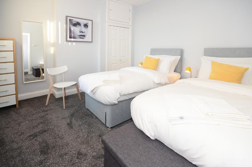 特伦特河畔斯托克Northwood Park East的一间卧室配有两张床、一把椅子和镜子