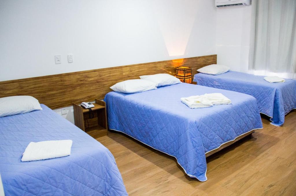 瓜拉派瑞Hotel Diamantina - By UP Hotel - em Guarapari的配有两张床铺的客房配有蓝色床单和白色枕头