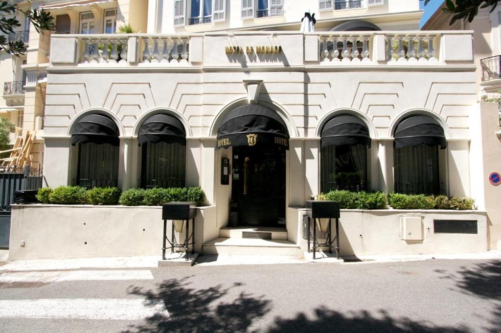 卡普戴尔摩纳哥酒店的一座白色的建筑,有黑色的门和一些植物