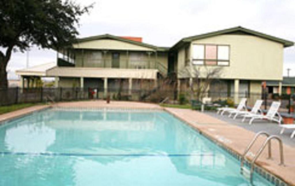 阿比林Econo Lodge Inn & Suites的一个带两把椅子的游泳池以及一座房子
